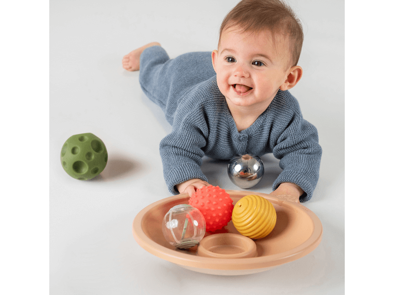 Schüssel mit Bällen zum Spielen auf dem Bauch